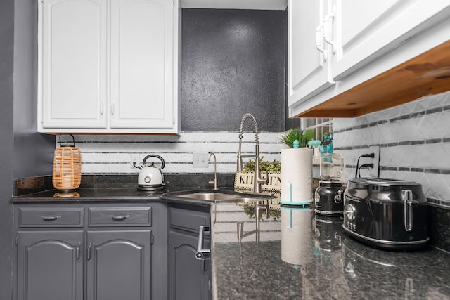 kitchen featuring white cabinetry, tasteful backsplash, dark stone countertops, sink, and gray cabinetry