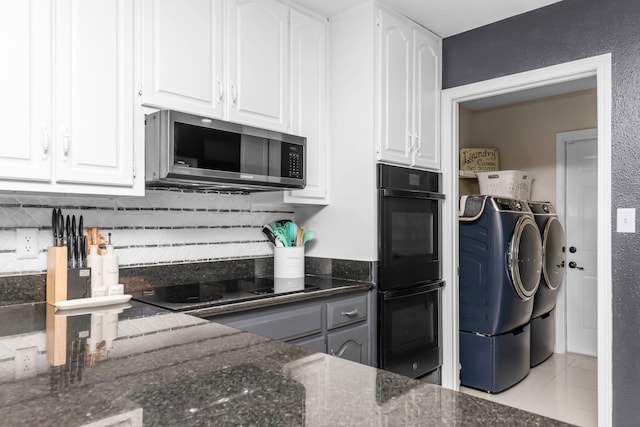 kitchen featuring washer and dryer, dark stone countertops, black appliances, white cabinetry, and light tile patterned floors