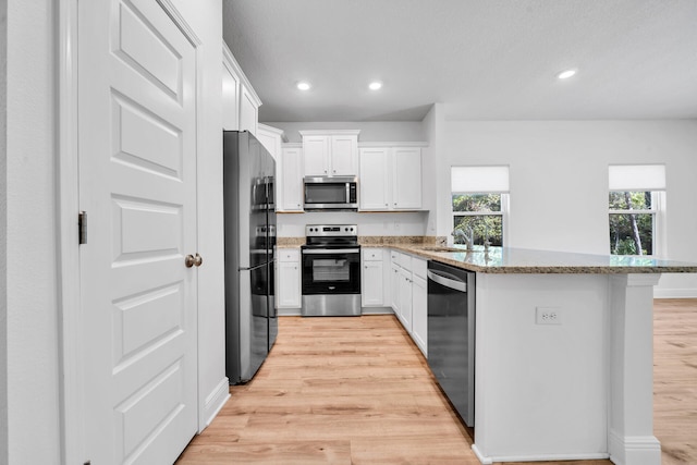 kitchen with light hardwood / wood-style floors, stainless steel appliances, and white cabinets