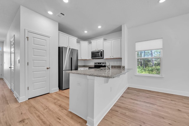 kitchen featuring appliances with stainless steel finishes, light hardwood / wood-style flooring, light stone countertops, and white cabinetry