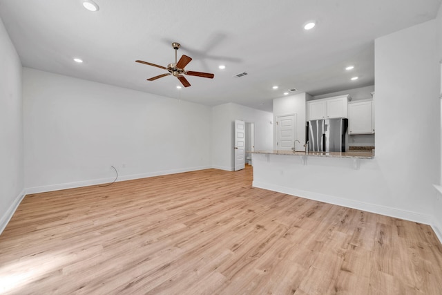 unfurnished living room featuring sink, ceiling fan, and light wood-type flooring