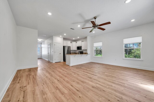 unfurnished living room featuring ceiling fan and light wood-type flooring