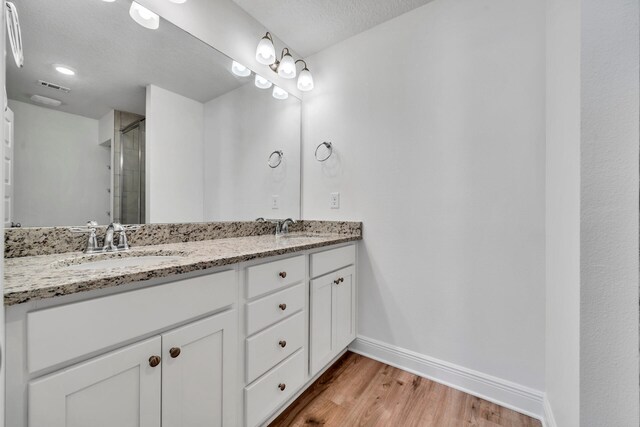 bathroom featuring a textured ceiling, double vanity, and hardwood / wood-style floors