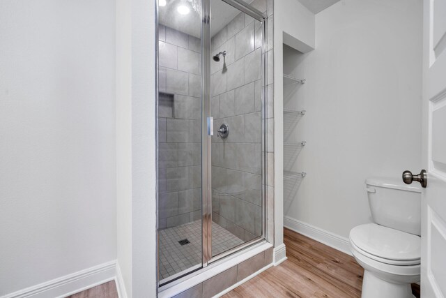 bathroom featuring a shower with door, hardwood / wood-style floors, and toilet