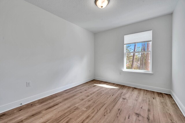 spare room with light hardwood / wood-style flooring and a textured ceiling