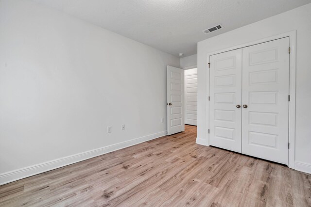 unfurnished bedroom featuring a closet and light wood-type flooring