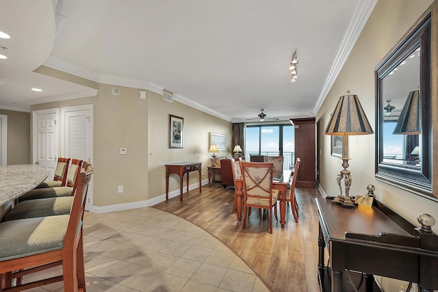 tiled dining space with ceiling fan and crown molding