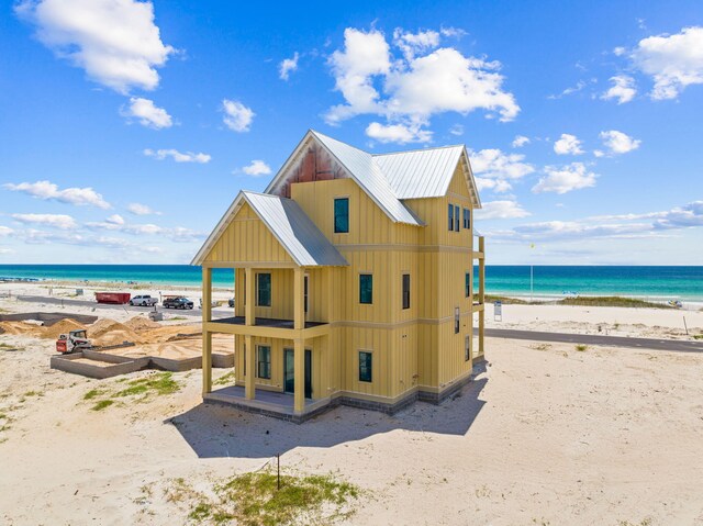 back of property with a water view and a beach view