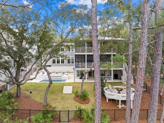 rear view of property with a fenced in pool, a patio area, an outdoor fire pit, and a yard