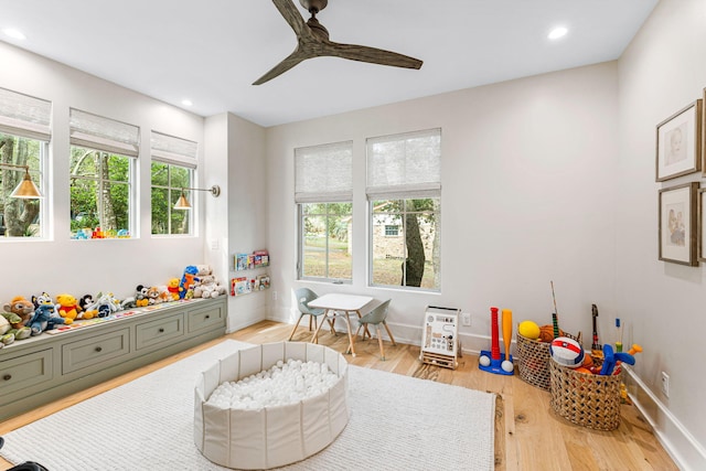 recreation room with light hardwood / wood-style floors and ceiling fan