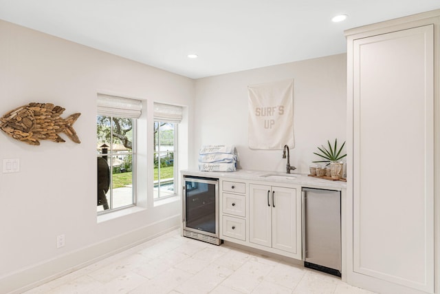 kitchen featuring white cabinetry, wine cooler, light tile floors, and sink