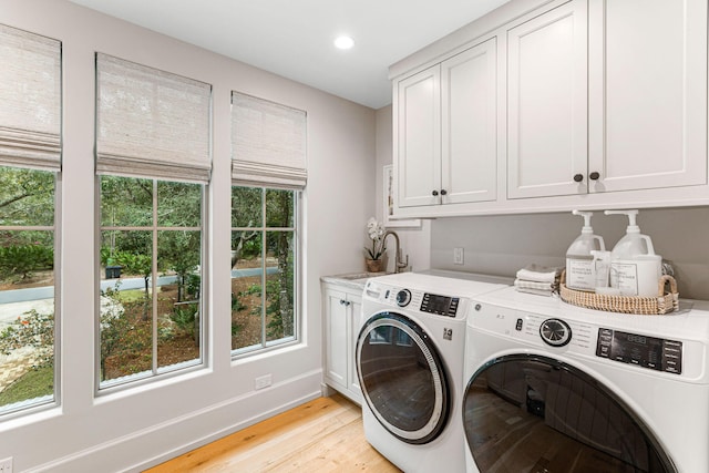 washroom featuring cabinets, light hardwood / wood-style flooring, separate washer and dryer, and a wealth of natural light