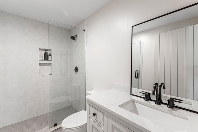 bathroom featuring a shower with door, vanity, and toilet