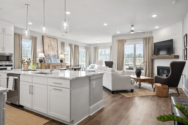 kitchen featuring white cabinetry, a brick fireplace, a healthy amount of sunlight, and ceiling fan