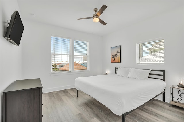 bedroom featuring hardwood / wood-style flooring, ceiling fan, and multiple windows