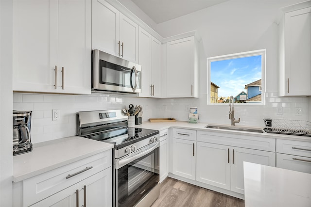 kitchen with backsplash, appliances with stainless steel finishes, sink, and light wood-type flooring