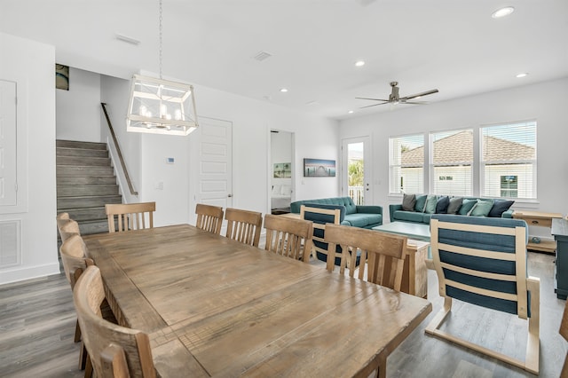 dining room with ceiling fan with notable chandelier and hardwood / wood-style flooring