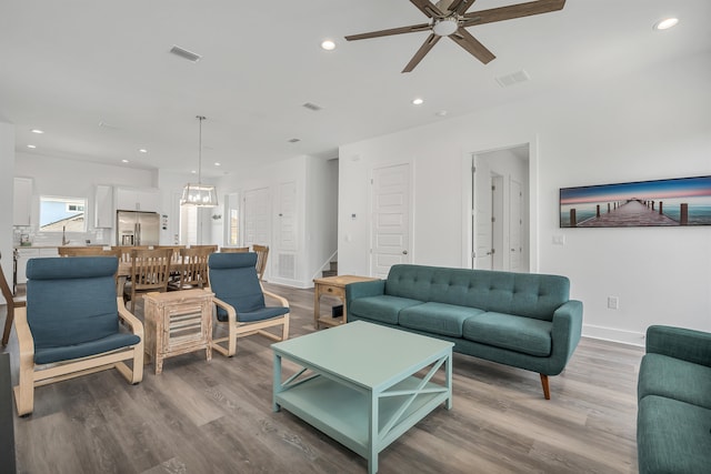 living room featuring ceiling fan with notable chandelier and hardwood / wood-style floors