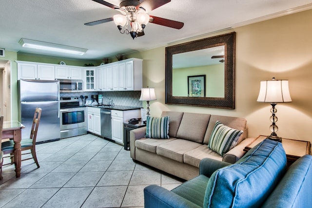 tiled living room with sink, ceiling fan, and crown molding