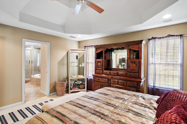 tiled bedroom with ensuite bath, a tray ceiling, and ceiling fan