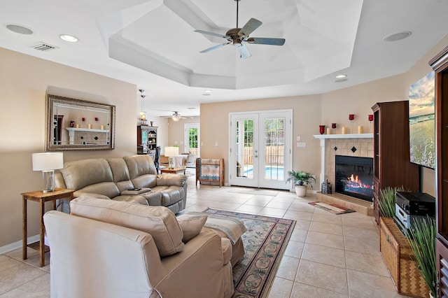 living room with french doors, a tiled fireplace, and light tile patterned floors