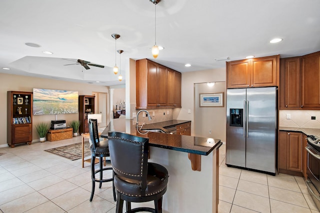 kitchen featuring tasteful backsplash, hanging light fixtures, a breakfast bar, sink, and stainless steel appliances