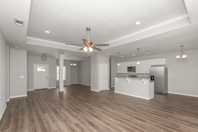 unfurnished living room featuring a textured ceiling, dark hardwood / wood-style floors, a raised ceiling, ornamental molding, and ceiling fan