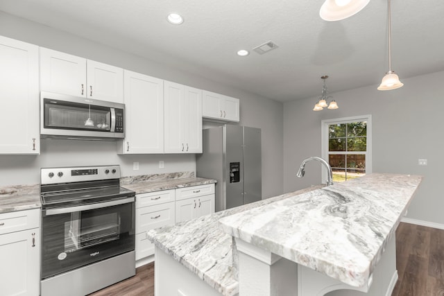 kitchen with a center island with sink, white cabinetry, dark hardwood / wood-style floors, and stainless steel appliances