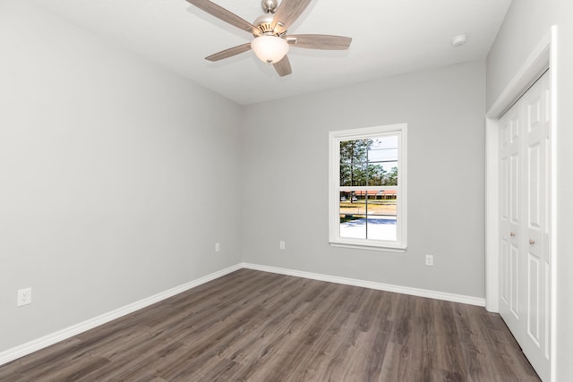 unfurnished bedroom featuring ceiling fan, a closet, and dark wood-type flooring