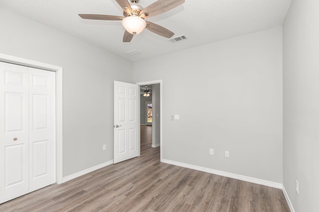 unfurnished bedroom featuring ceiling fan, a textured ceiling, a closet, and light wood-type flooring