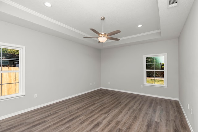 unfurnished room with dark wood-type flooring, a textured ceiling, a tray ceiling, ceiling fan, and ornamental molding