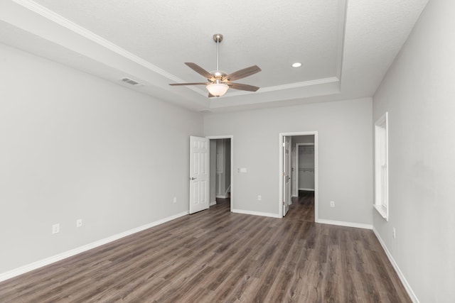 unfurnished bedroom with a closet, a textured ceiling, dark hardwood / wood-style flooring, a spacious closet, and ceiling fan