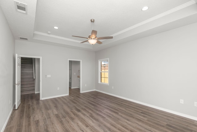 unfurnished bedroom with a closet, a raised ceiling, dark hardwood / wood-style flooring, ornamental molding, and ceiling fan