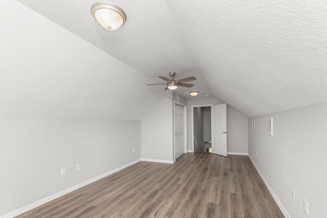 bonus room with lofted ceiling, a textured ceiling, dark hardwood / wood-style floors, and ceiling fan