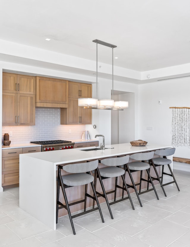 kitchen with pendant lighting, a kitchen island with sink, light tile floors, and range