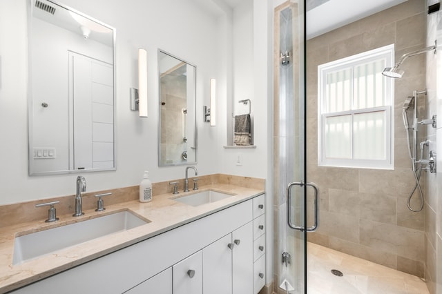 bathroom featuring double vanity and a shower with shower door