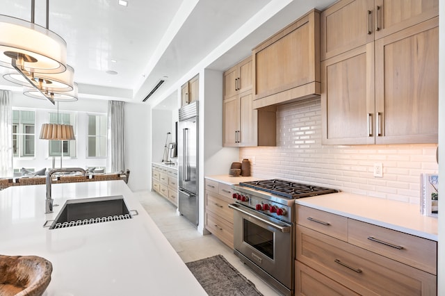 kitchen featuring hanging light fixtures, light tile flooring, tasteful backsplash, premium appliances, and sink