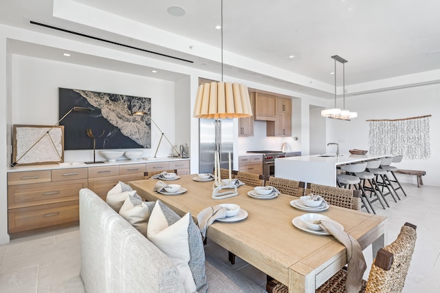 tiled dining space with a raised ceiling, a notable chandelier, and sink