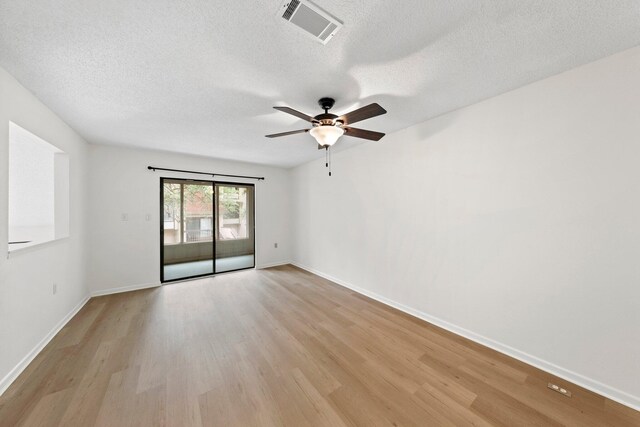 empty room with ceiling fan, light hardwood / wood-style flooring, and a textured ceiling