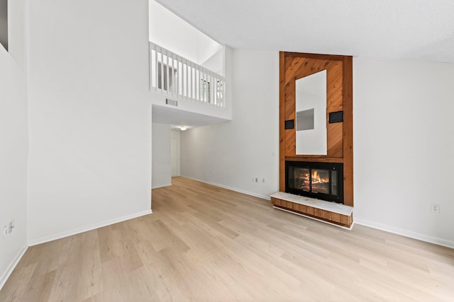 unfurnished living room with high vaulted ceiling, light hardwood / wood-style floors, and wooden walls