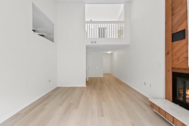 unfurnished living room featuring light hardwood / wood-style flooring and a towering ceiling