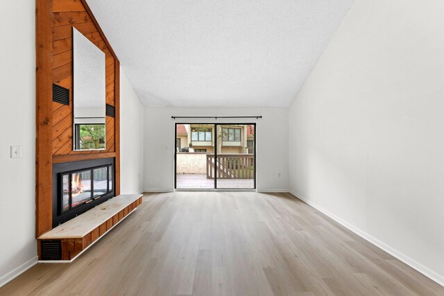 unfurnished living room featuring light hardwood / wood-style flooring and a textured ceiling