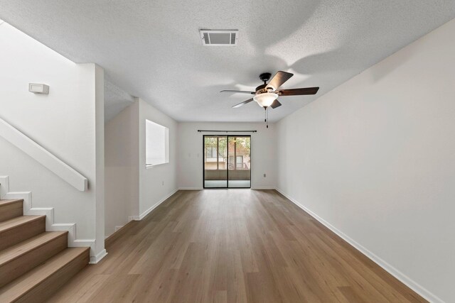 spare room with light hardwood / wood-style floors, ceiling fan, and a textured ceiling