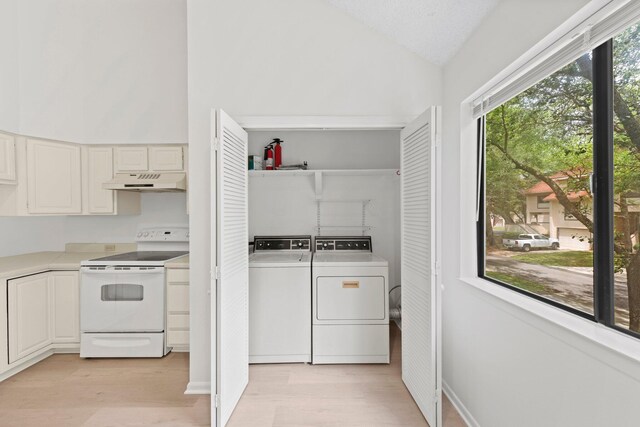 kitchen featuring washer and dryer, light wood-type flooring, white cabinetry, white electric range, and lofted ceiling