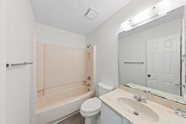 full bathroom with  shower combination, vanity, hardwood / wood-style floors, toilet, and a textured ceiling