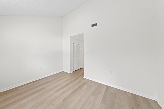 spare room with high vaulted ceiling and light hardwood / wood-style floors