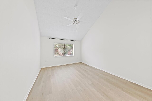 empty room with ceiling fan, light hardwood / wood-style flooring, vaulted ceiling, and a textured ceiling