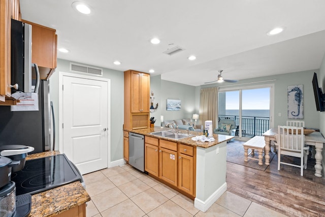 kitchen with light stone counters, sink, light hardwood / wood-style floors, stainless steel appliances, and kitchen peninsula