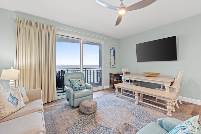 living room featuring dark hardwood / wood-style flooring, ceiling fan, and a water view