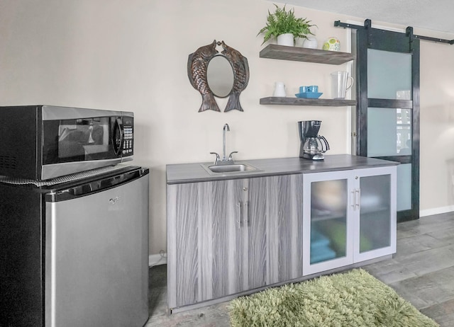 interior space with a barn door, wood-type flooring, sink, and fridge